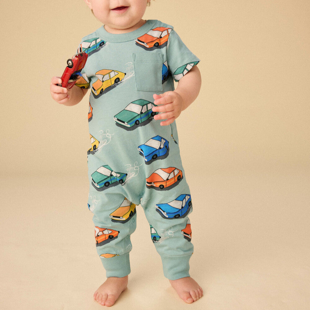 Baby wearing a onesie with car patterns on a beige background