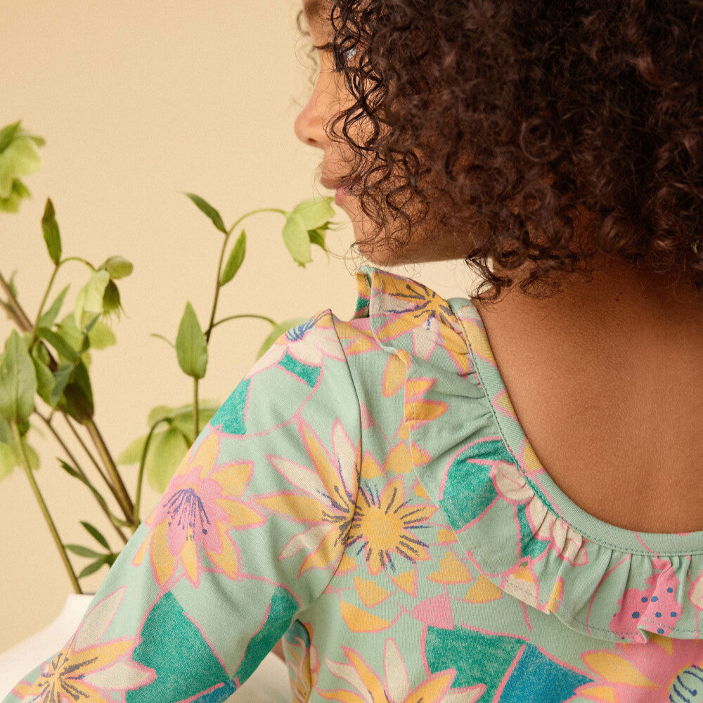 Person wearing a colorful floral dress with a plant in the background