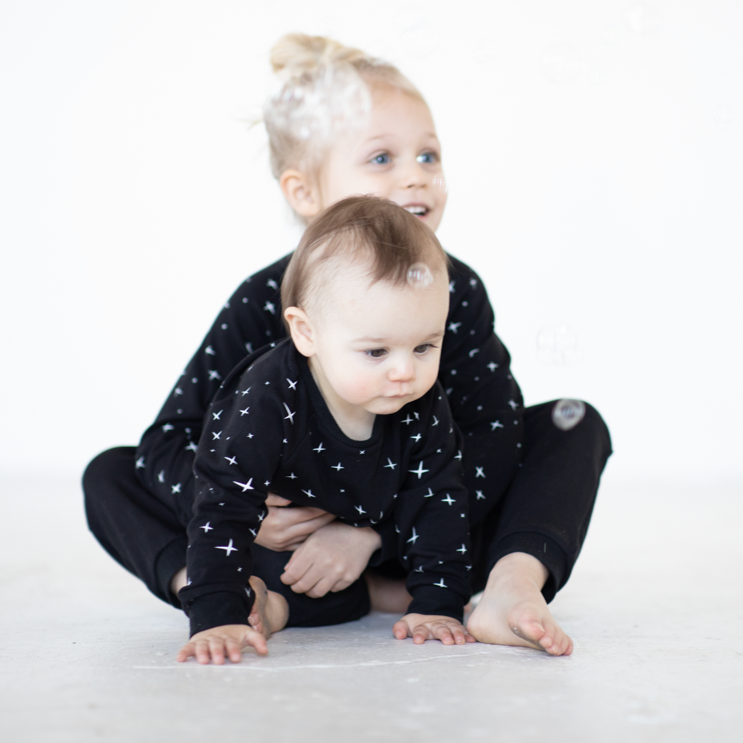 toddler holding baby in peregrine black bamboo sweatshirt and sweatpants