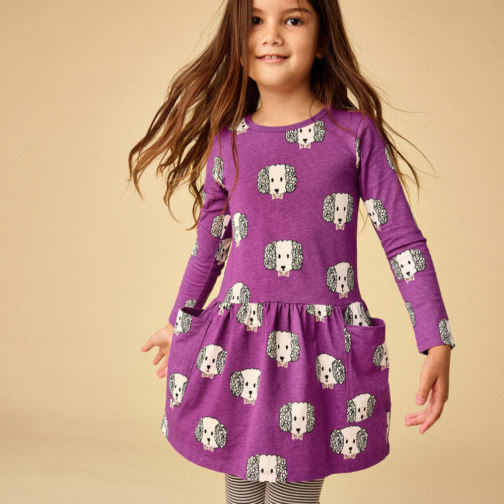 Young girl wearing a purple dress with dog pattern on a beige background