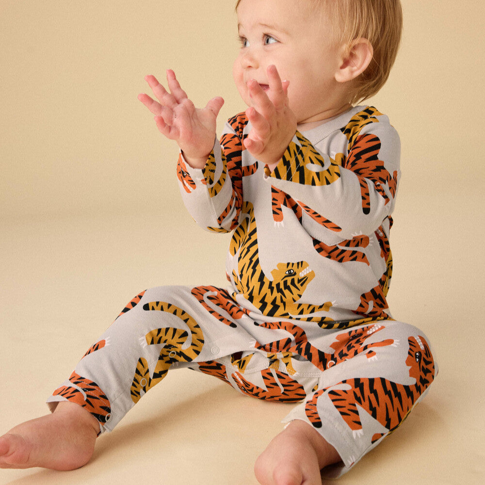 Baby wearing a tiger print onesie on a beige background