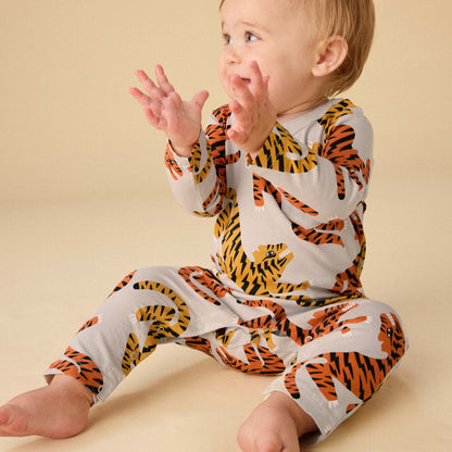 Baby wearing a tiger print onesie on a beige background