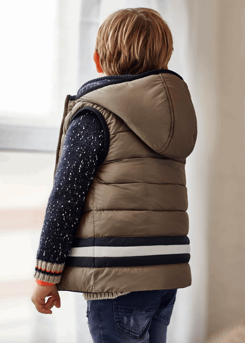 a boy is shown wearing a tan puffer vest with black and white stripes